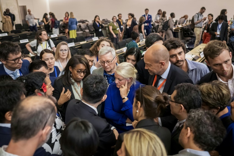 Des délégués de plusieurs gouvernements se concertent dans la grande salle des Nations Unies après l'annonce d'une extension dans la durée des négociations dans l'espoir de parvenir à un accord sur un texte de traité contre la pollution plastique, jeudi 14 aout 2025 à Genève