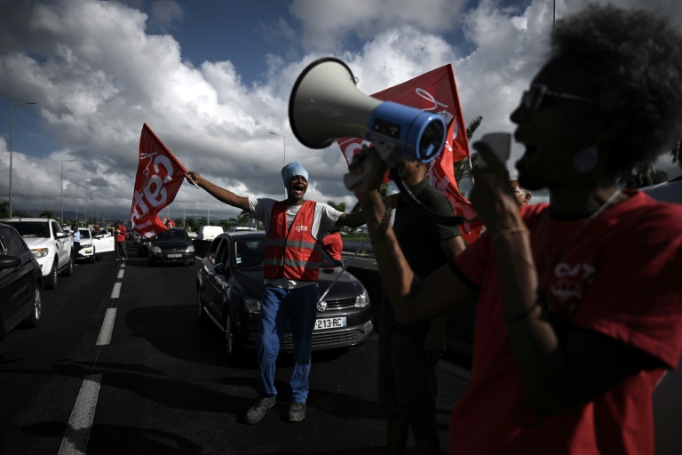 Des membres de la CGT Martinique manifestent le 15 octobre 2024 sur la route menant à l'aéroport de Fort-de-France, en plein mouvement contre la vie chère