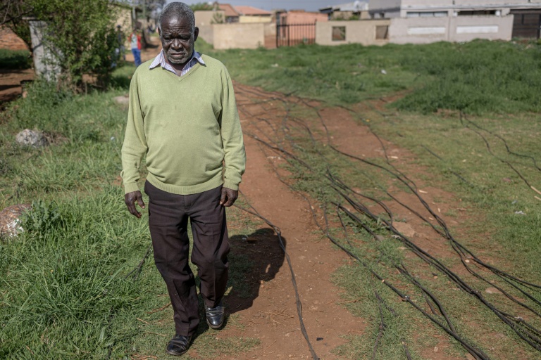 Un habitant du township de Katlehong, près de Johannesburg, marche à côté des câbles qui raccordent illégalement son quartier au réseau électrique, le 5 octobre 2026