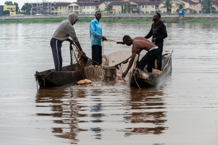 Des pêcheurs récupèrent des déchets plastiques pris dans l'un de leurs filets sur le fleuve Congo à Kinshasa, le 27 avril 2026 en RDC