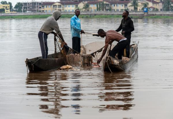 Des pêcheurs récupèrent des déchets plastiques pris dans l'un de leurs filets sur le fleuve Congo à Kinshasa, le 27 avril 2026 en RDC