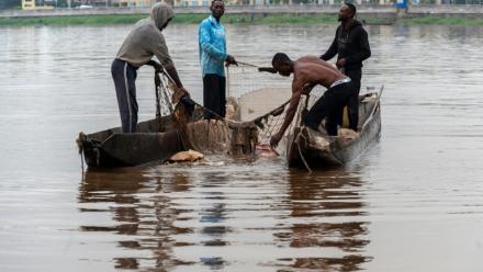 Des pêcheurs récupèrent des déchets plastiques pris dans l'un de leurs filets sur le fleuve Congo à Kinshasa, le 27 avril 2026 en RDC