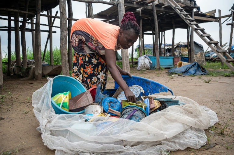 Une femme trie des objets en plastique ramassés dans le fleuve Congo sur l'île de Kimpoko, à Kinshasa, le 27 avril 2026 en RDC