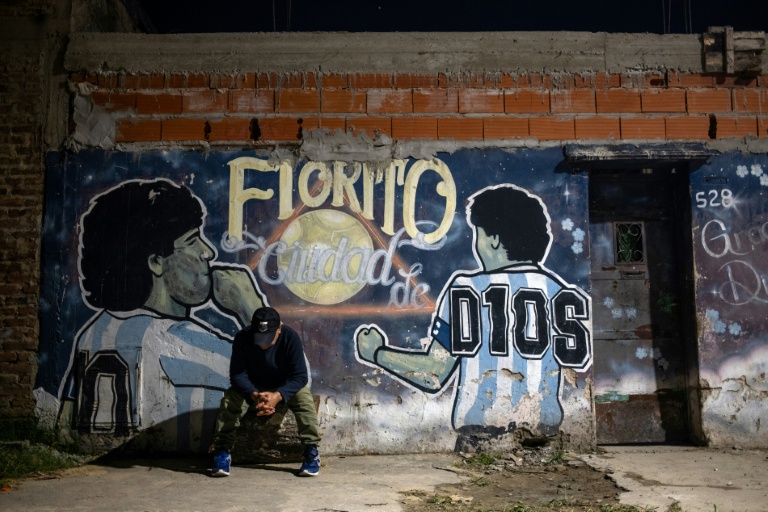 Un homme est assis devant une fresque murale représentant Diego Maradona, dans la cour de la maison où a grandi la légende du football, à Villa Fiorito, dans la province de Buenos Aires, en Argentine, le 9 avril 2026
