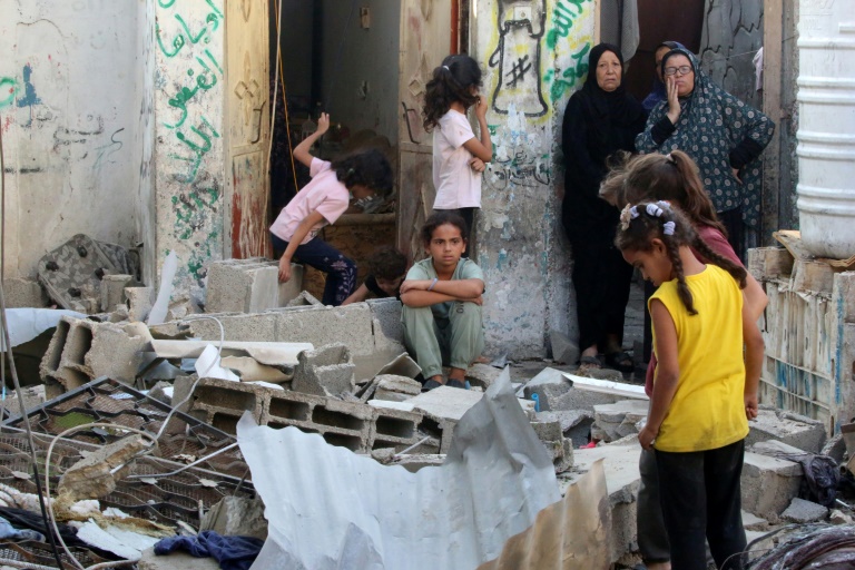 Des femmes et des enfants palestiniens au milieu des décombres d'une maison après une frappe israélienne sur le camp de Nousseirat, dans le centre de la bande de Gaza, le 27 septembre 2025 