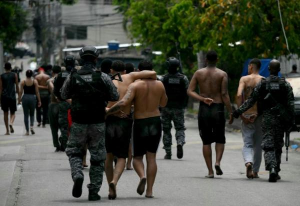 Des policiers escortent des criminels présumés arrêtés lors d'une opération dans la favela de Vila Cruzeiro, dans le complexe de Penha, à Rio de Janeiro, le 28 octobre 2025 au Brésil