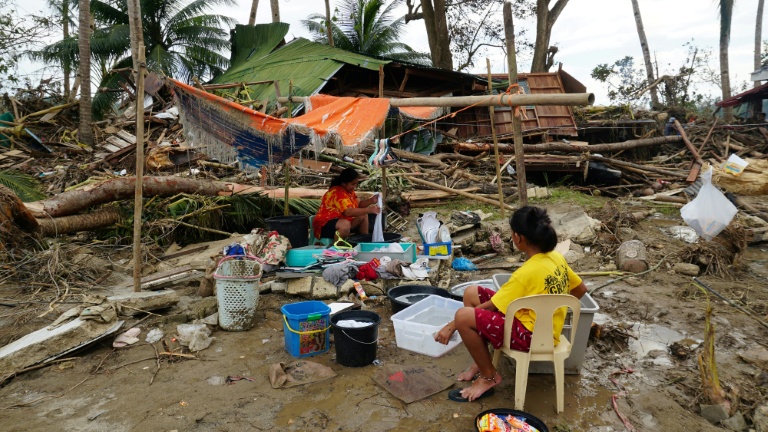Des habitants près de leur maison détruite par le passage du typhon Rai, le 21 décembre 2021 à Loboc, dans la province de Bohol, aux Philippines