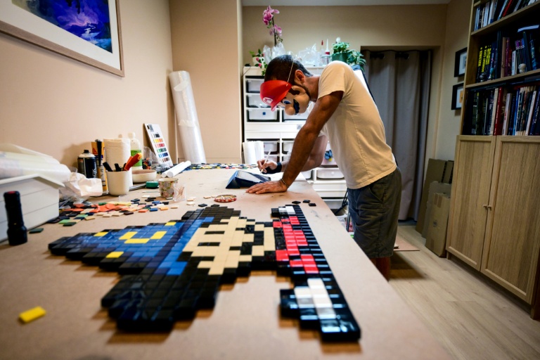 Le street-artiste In The Woup travaille sur une mosaïque inspirée de l'univers 