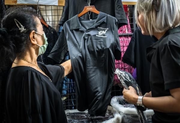 Des clients achètent des vêtements noirs à Bangkok le 30 ocobre 2025 pour porter le deuil après le décès de la reine mère Sirikit,  décédée à 93 ans