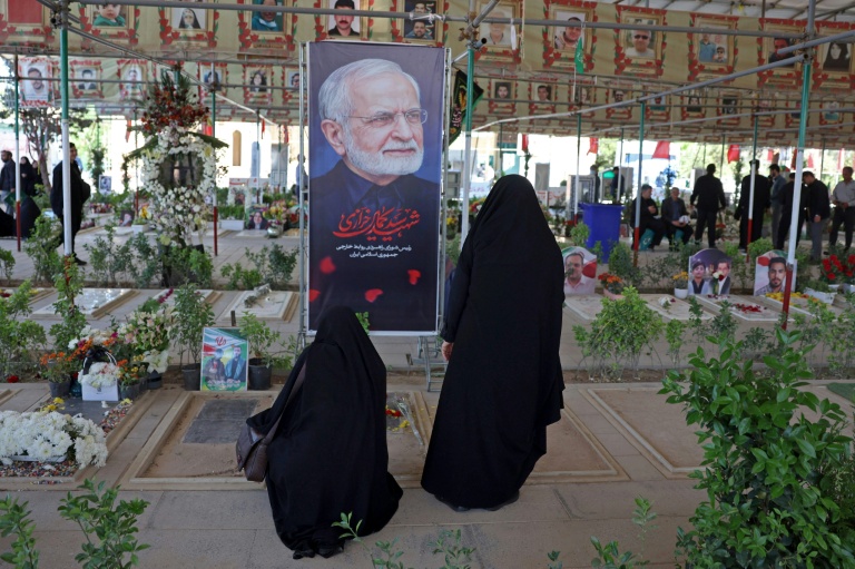 Deux femmes se recueillent devant la tombe de l'ancien ministre iranien des Affaires étrangères Kamal Kharazi, mort le 1er avril des suites de ses blessures après des frappes israélo-américaines, dans un cimetière du sud de Téhéran, le 23 avril 2026