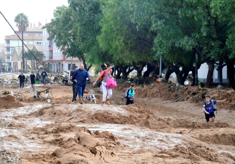 Une famille marche dans une rue envahie par la boue après les inondations qui ont touché la région de Valence, le 30 octobre 2024 à Picanya, en Espagne