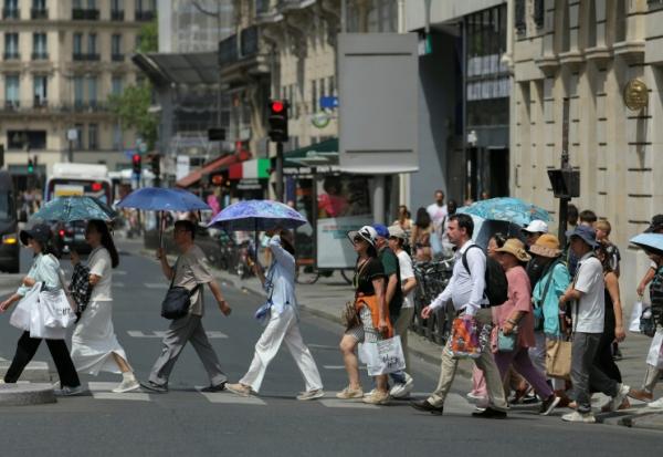 Des touristes se protègent du soleil sous des parapluies à Paris le 23 juin 2026