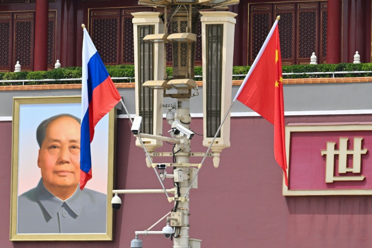 Le drapeau national russe (g) flotte à côté du drapeau chinois près d'un portrait du défunt dirigeant communiste Mao Tsé-toung devant la porte de Tiananmen, lors de la visite d'Etat du président russe Vladimir Poutine à Pékin, le 16 mai 2024