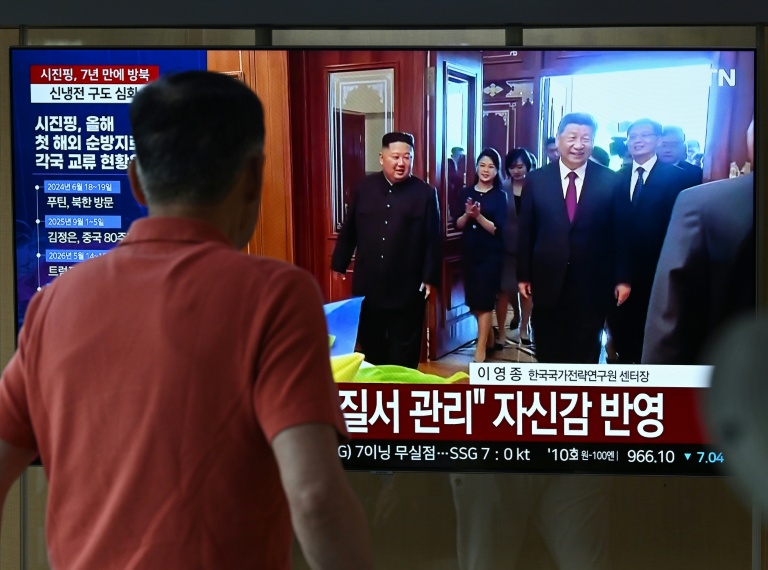 Un homme passe devant un écran de télévision diffusant un journal télévisé avec des images d'archives de la rencontre de 2019 entre le président chinois Xi Jinping et le dirigeant nord-coréen Kim Jong Un, dans une gare de Séoul, le 8 juin 2026