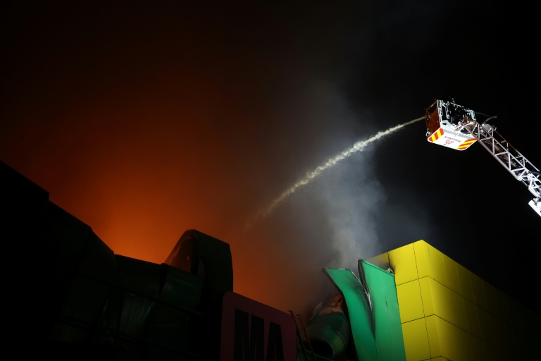 Des pompiers sur le site d’un centre commercial endommagé par une frappe de missile russe à Kiev, le 22 octobre 2026 en Ukraine